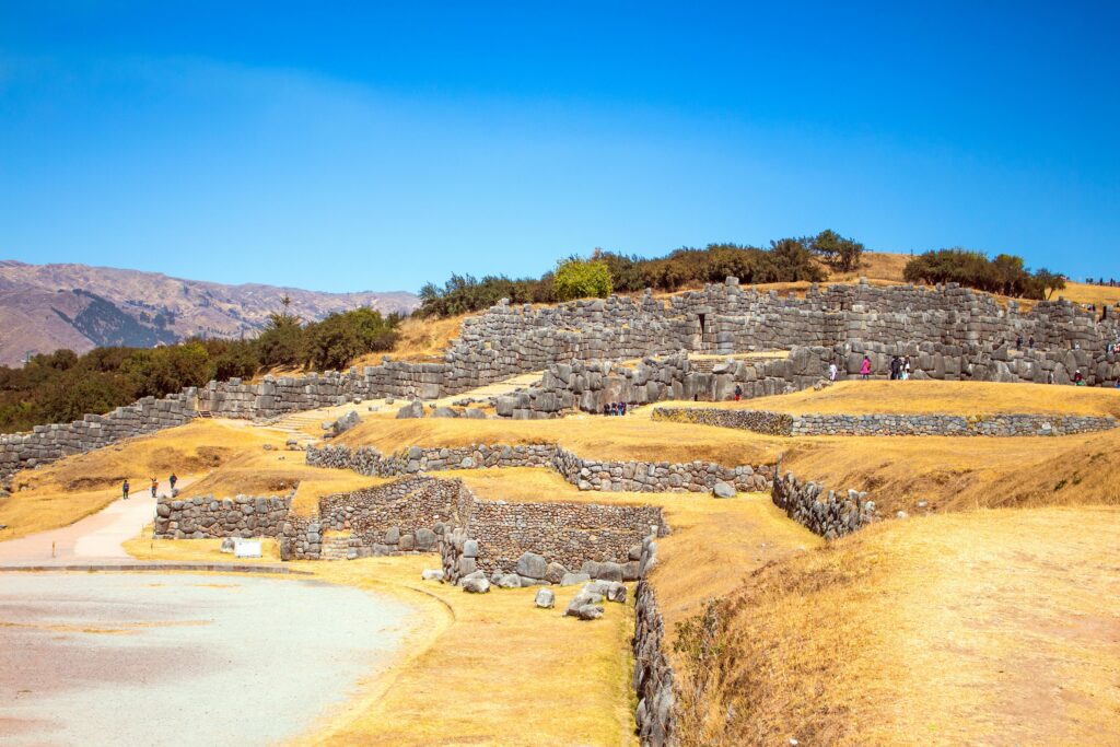 Explore the ancient stone ruins of Sacsayhuamán under a clear blue sky in Cusco, Peru.